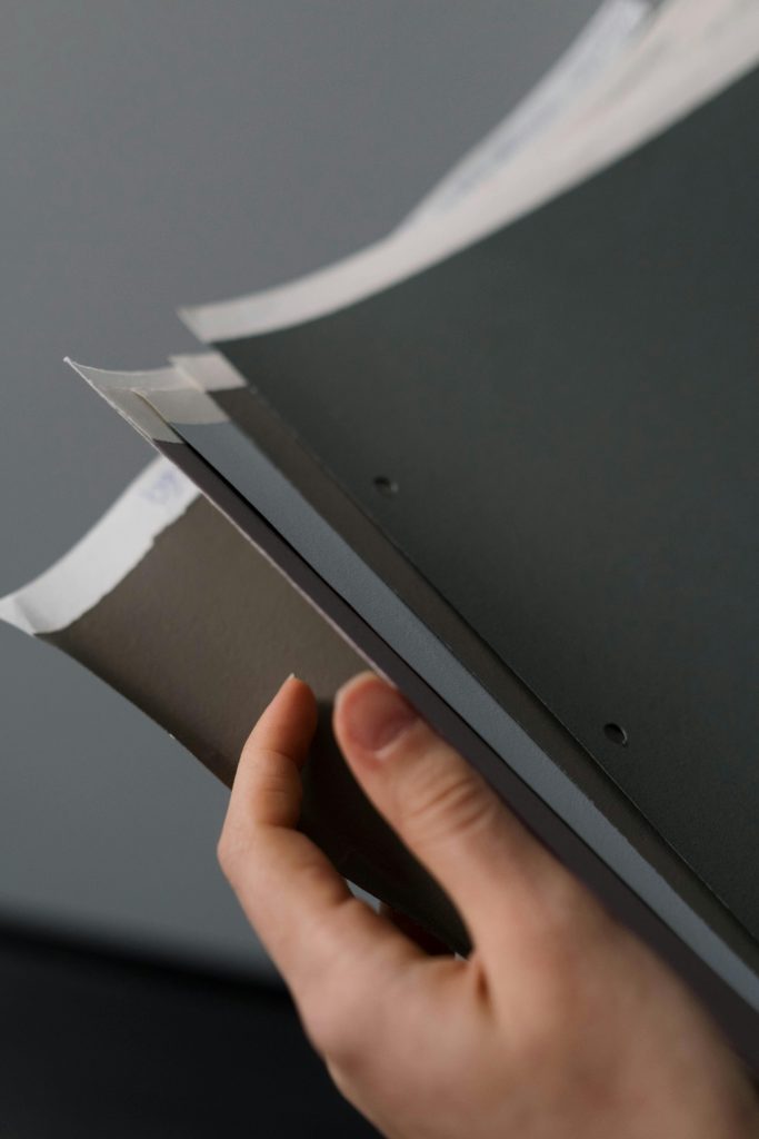 A close-up view of a hand holding paper samples, showcasing different textures and colors.